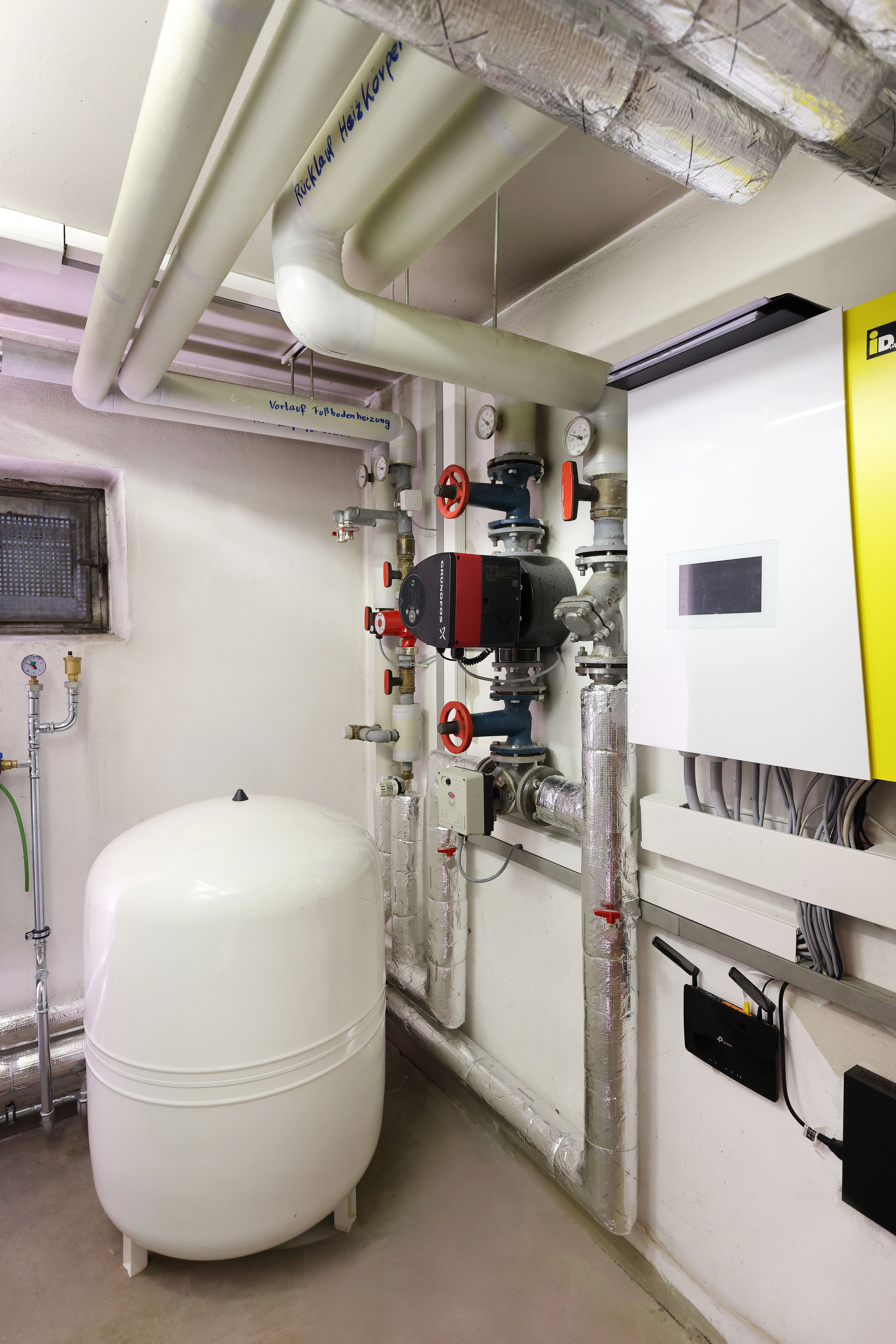 Technikraum mit neuer iDM-Heizungsanlage, Pumpengruppe, Verrohrung und Regelungstechnik im Mehrfamilienhaus.