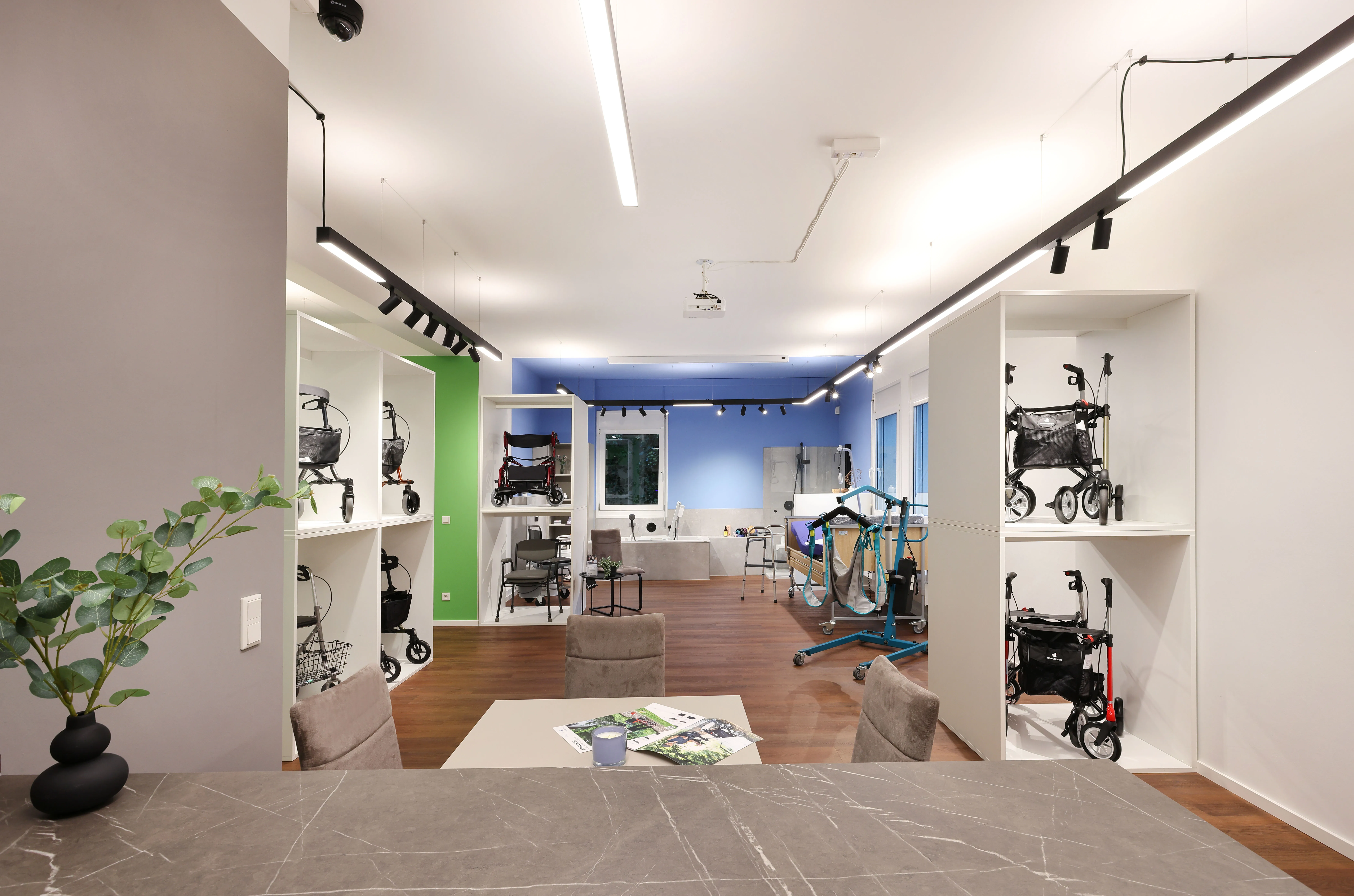 Innenansicht eines modernen Reha-Fachgeschäfts mit Präsentationsregalen für Rollatoren und Gehhilfen, heller Beleuchtung und Holzboden.