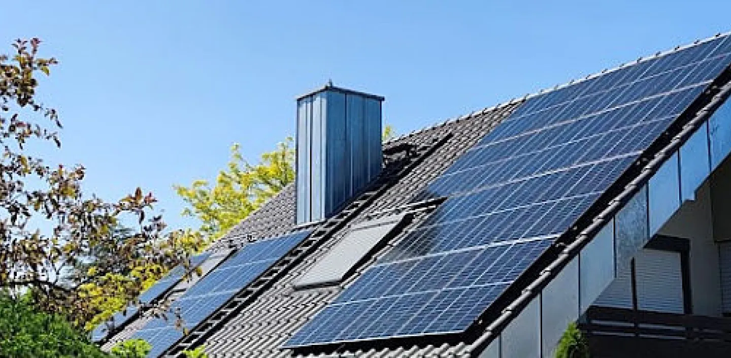 Einfamilienhaus mit Solarmodulen auf dem Dach, umgeben von grünem Garten.