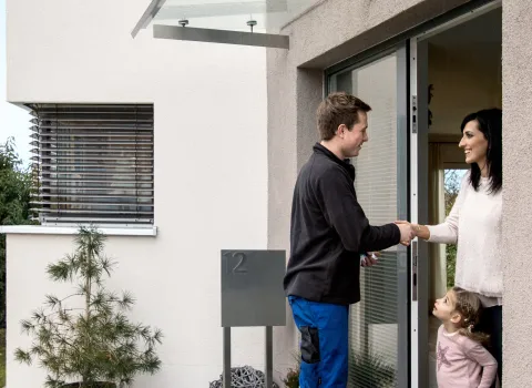 Kundendiensttechniker (SHK) begrüßt Kundin mit Kind bei einem Service-Einsatz