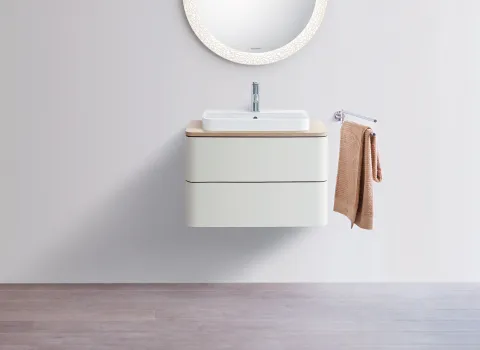 Elegantes Gästebadmöbel mit schwebendem weißen Waschtisch, rundem Spiegel und beigem Handtuchhalter. Minimalistisches Design.