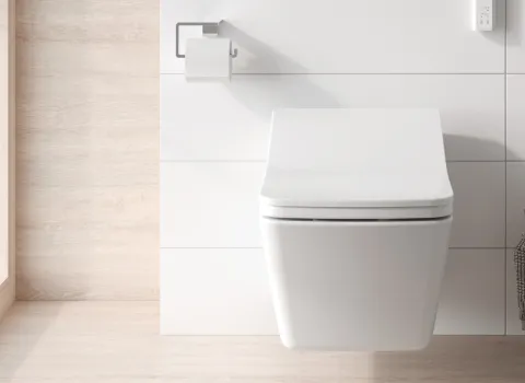 Ein wandhängendes TOTO-SX-WC in Weiß vor einer hellen, gefliesten Wand mit modernem Papierhalter.