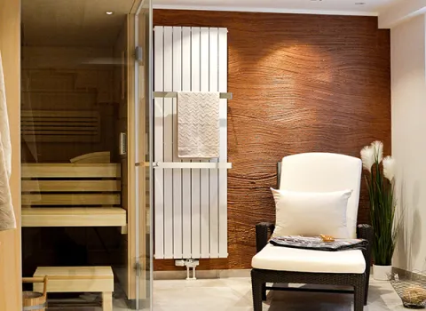 Ein Sessel in einem Wellnessbad mit Sauna in warmen Tönen.