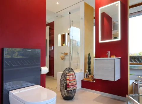 Ein Foto einer Badreferenz mit WC, bodengleicher Dusche und roter Wandfarbe aus der Badausstellung von Kreuz Schnaittach.