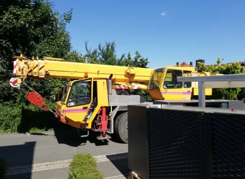 Mobiler gelber Kran beim Anfahren und Positionieren zur Installation einer großen Wärmepumpenanlage.