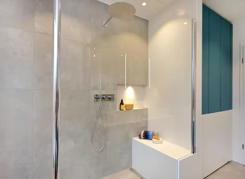 Große, barrierearme Dusche mit Sitzbank, Glasabtrennung und Regendusche in einem modernem Familienbad.