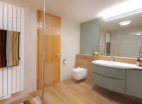 Modernes Badezimmer mit Holzoptikboden, schwebendem Waschtisch in Salbeigrün und bodengleicher Dusche.