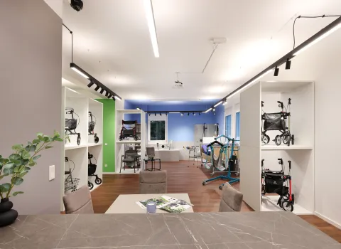 Innenansicht eines modernen Reha-Fachgeschäfts mit Präsentationsregalen für Rollatoren und Gehhilfen, heller Beleuchtung und Holzboden.