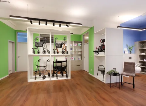 Ausstellungsfläche mit Rollatoren in weißen Regalen, grüner Wandgestaltung und moderner Einrichtung im Reha-Fachhandel.