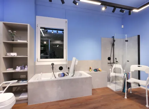 Barrierefreies Musterbad mit Badewanne, Dusche, Duschstuhl und Ablagen – gezeigt in einer Reha- und Pflegeausstellung.