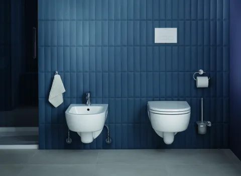 Wc und Bidet von Duravit aus der Kollektion D-Code vor Wand mit blauen Fliesen.