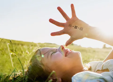 Kind mit Wärme und Strom Symbolen auf der Hand auf grüner Wiese.