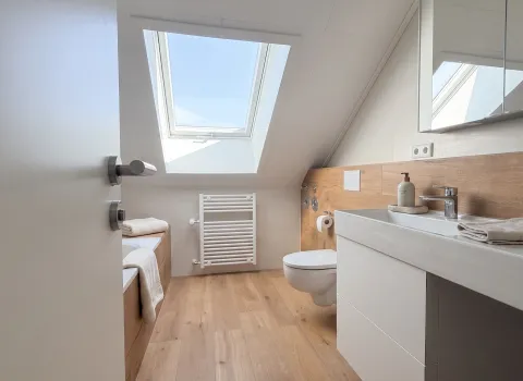 Modernisiertes Badezimmer mit Holzoptik, Waschtisch und Dachfenster in Eckental.
