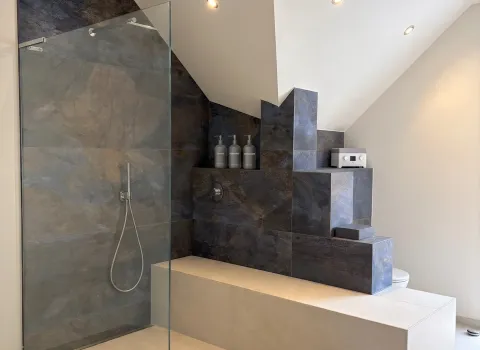 Modernes Badezimmer in Hersbruck mit bodengleicher Dusche, Glasabtrennung und großformatigen Fliesen.