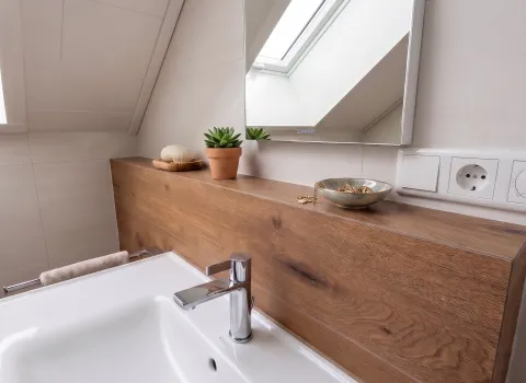 Weißer Waschtisch mit Holzrückwand und Spiegel im Badezimmer in Eckental.