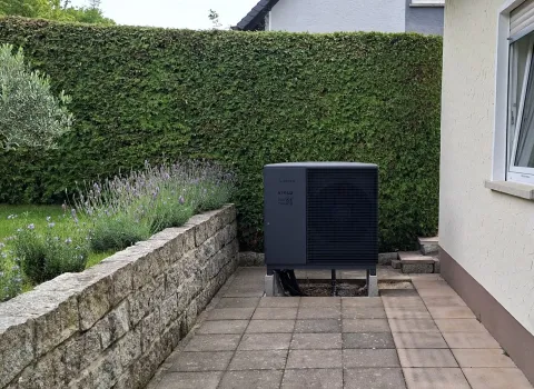 Außeneinheit einer Luft-Wärmepumpe in Schnaittach neben einem Wohnhaus.