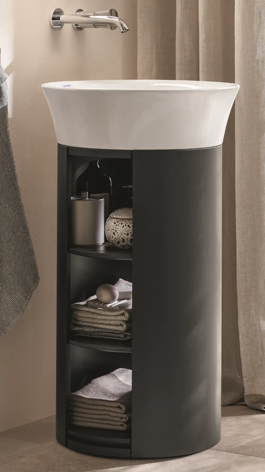 Ein modernes Standwaschbecken in einem schwarzen Unterschrank mit offenen Regalen, die Handtücher und dekorative Gegenstände wie eine Seifenschale und einen Kerzenhalter enthalten.