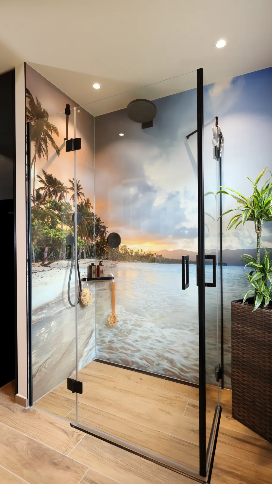 Eine Dusche mit fugenloser Wandgestaltung mit einem Strandmotiv und schwarzen Armaturen.