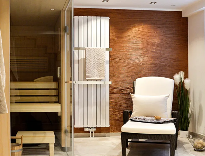 Ein Sessel in einem Wellnessbad mit Sauna in warmen Tönen.