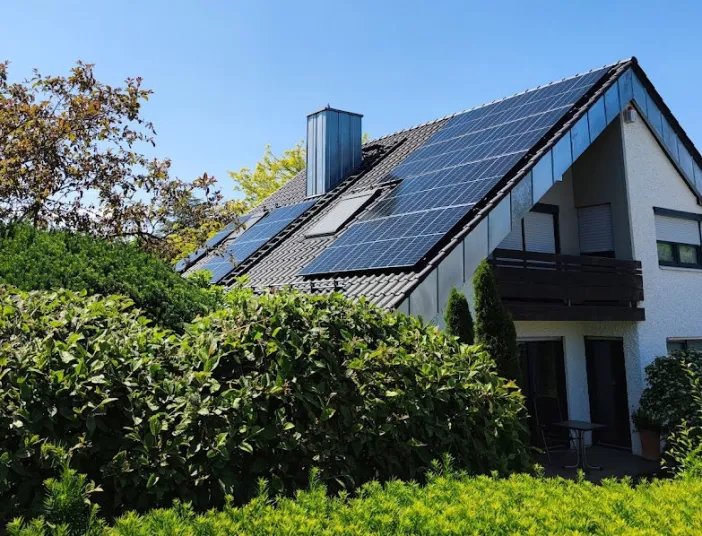 Einfamilienhaus mit Solarmodulen auf dem Dach, umgeben von grünem Garten.