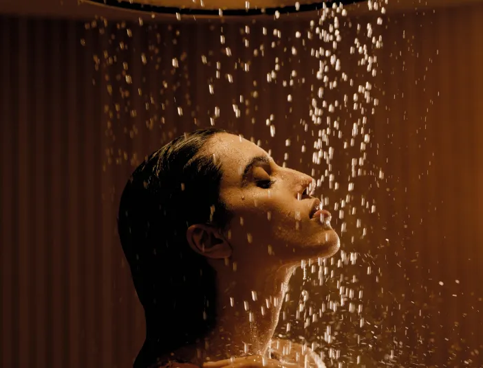 Eine Frau, die in der Aquahalo-Erlebnisdusche von Dornbracht duscht.